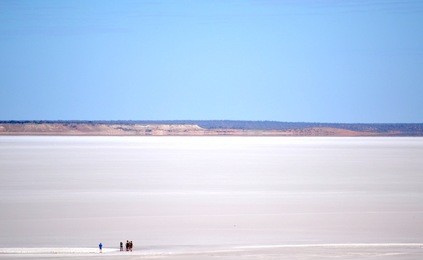 people in the distance walking on a remote outback salt lake in australia
