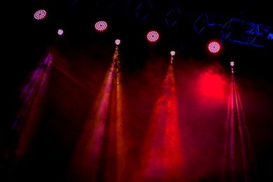 stage lights. several projectors in the dark. multi-colored light beams from the stage spotlights on the stage in the smoke at the time of the entertainment show. night club