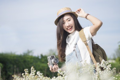 asian hipster cute teen girl with camera in white flower garden,  vintage tone travel and relax with nature concept. 