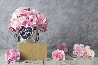 pink carnation flowers in zinc bucket with happy mother,s day letter on wood heart and blank brown card