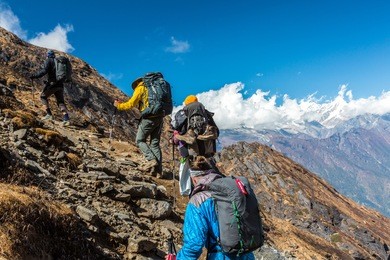 group of people walking up on steep mountain trail using hiking gear carrying backpacks