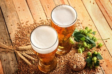 glasses with fresh beer and ingredients on wooden background
