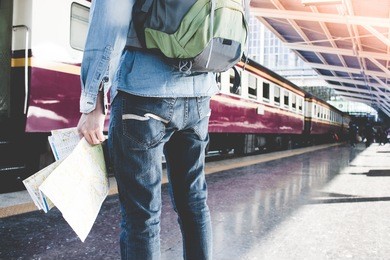 young man holding map standing on platform at train station for travel. travel concept by train.
