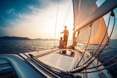 couple enjoying sunset from the deck of the sailing boat moving in a sea