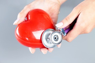 female medicine doctor hold in hands red toy heart and stethoscope head. cardio therapeutist, student education, physician make cardiac physical,  rate measure, arrhythmia concept