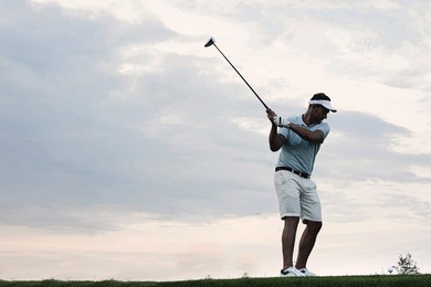 mid-adult man playing golf against sky