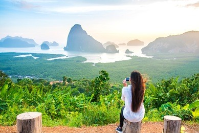woman is taking photo with cell telephone camera of phang nga bay islands,thailand.