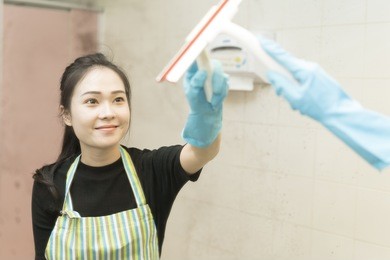 housekeeping or maid cleaning a dirty mirror in a toilet
