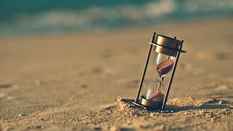 hourglass on a sand dune beach. (vintage style)