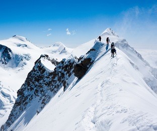 climbers balancing in blizzard on a narrow ridge of lyskamm (aka maneater, 4480 m)