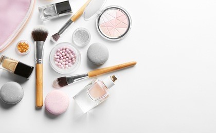 makeup products with cosmetic bag and macaroons on light background