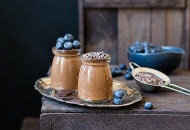 chocolate mousse with blueberry in a glasses on a wooden background.