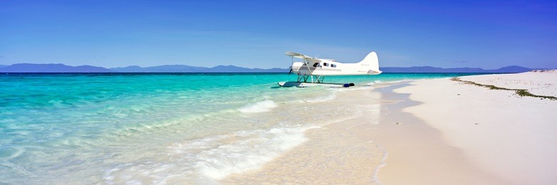 a seaplane on a white sand beach with blue water