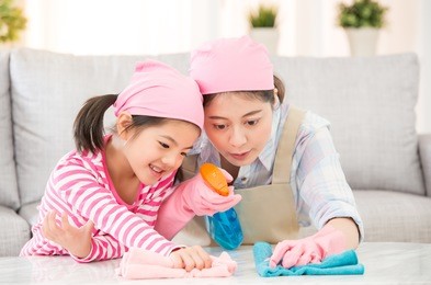 mixed race asian chinese mother and daughter do the cleaning in the house. happy family cleans the room. a young woman and a little child girl dusting. family housework and household concept.