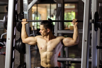 asian man exercising with barbell in gym.