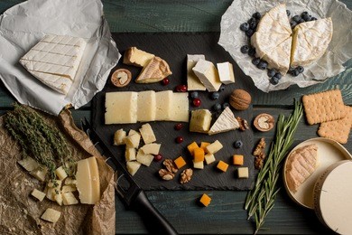 tasting cheese dish with herbs and fruits on old black wooden table. food for wine and romantic, cheese delicatessen. menu design horizontal. top view.