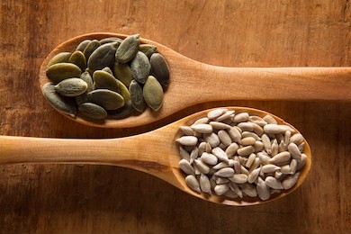 food ingredients in wooden spoon on wooden background. pumpkin seed and sunflower seed