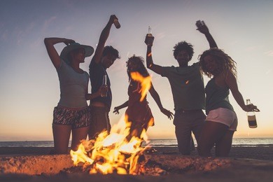 multicultural group of friends partying on the beach - young people celebrating during summer vacation, summertime and holidays concepts