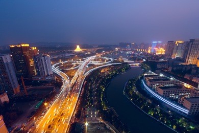 it is at nightfall. there are giant overpasses near a river which shows the high speed of city life.