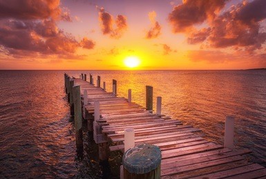 dock during caribbean sunset, beautiful magenta colors and perspective of this boat dock and fishing dock in eleuthera island, bahamas