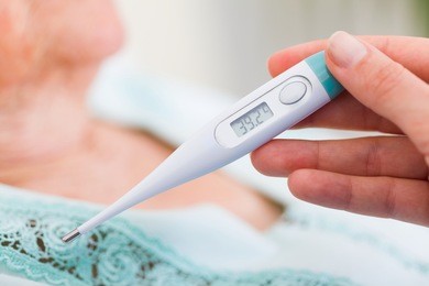 carer checking elderly patients fever in the nursing home - virus infection.