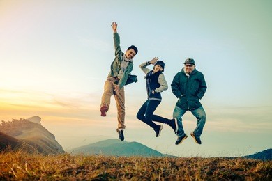 group of asian friends having fun jumps on sunset and mountains with filter effect