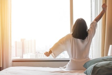 easy lifestyle asian woman waking up in the morning taking some rest relaxing in hotel room for world lazy day concept