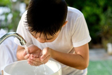 selective focus brand new faucet and kid hand taking water to wash.