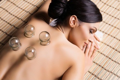 beautiful, young and healthy woman on bamboo mat in spa salon is having vacuum cupping. spa, health and healing concept. 