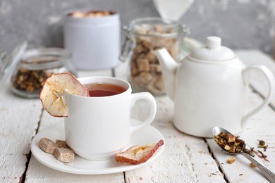 apple tea served in white cup on white table. hot drink for winter. selective focus
