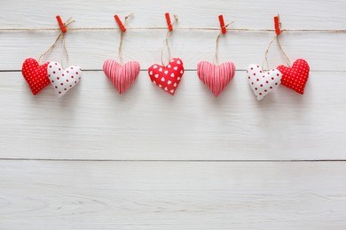 valentine background with sewed pillow diy handmade hearts row border on red clothespins at rustic white wood planks. happy lovers day card mockup, copy space