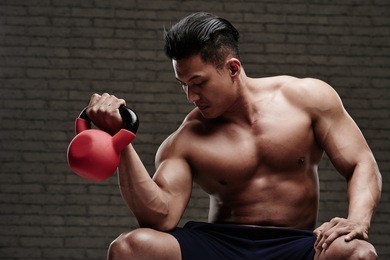 sporstman doing exercise for biceps with kettlebell