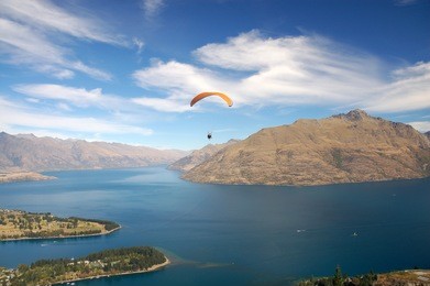 a hang-glider floating over queenstown, new zealand
