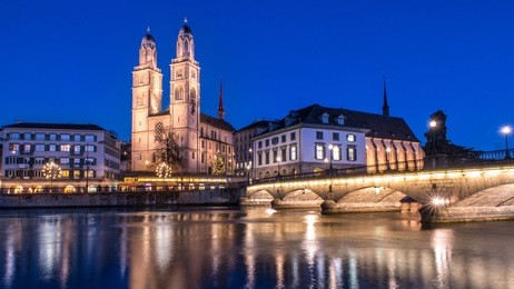 view of the grossmunster (great minster) church and the limmat river at night, zurich, switzerland