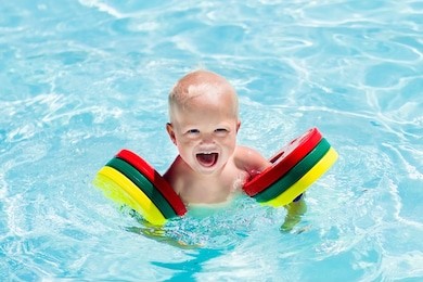 happy laughing baby boy playing in outdoor swimming pool on a