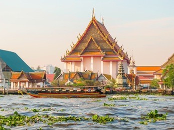 chao phraya river and wat arun temple at sunrise. thai traditional boat and ancient temple at sunrise light. bangkok, thailand