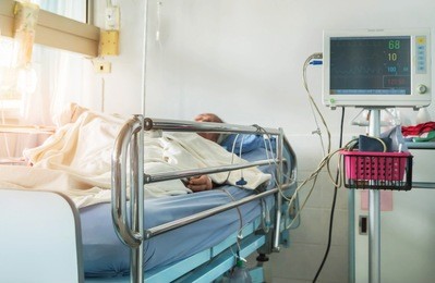close up bed of  hospital ward room during elderly patient sleep with digital device for measuring blood pressure monitor