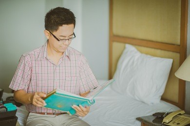 young asian business man reads a paper in his room before a conference 