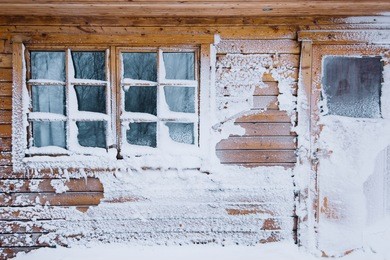 winter wooden house wall covered with snow after severe blizzard