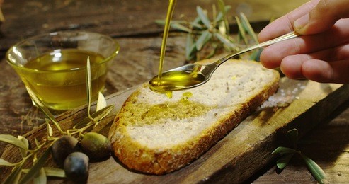 genuine italian organic oil cold pressed in slow motion falls on organic bread. concept of nature and healthy food, healthy and natural. fresh olives and tuscan italian oil