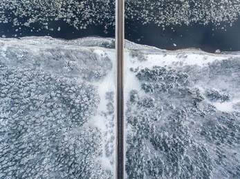 winter season aerial top down view of a bridge with a straight line road over river nemunas.