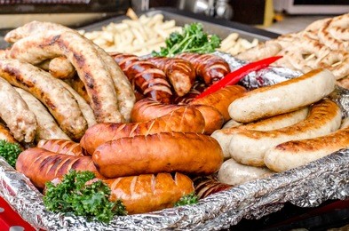 assorted sausages grilled on skewers on a large plate, mushrooms on the grill. street festival food.