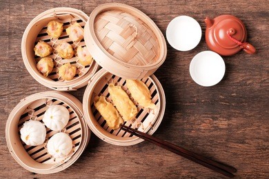 dim sum(chinese cuisine) in bamboo steamed and teapot on wooden table top.