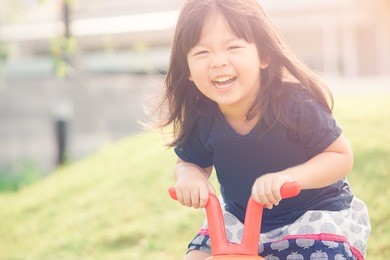 happy little asian girl smile and rid a bike  in sunset time.