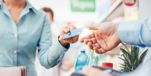 woman at the supermarket checkout, she is paying using a credit card, shopping and retail concept