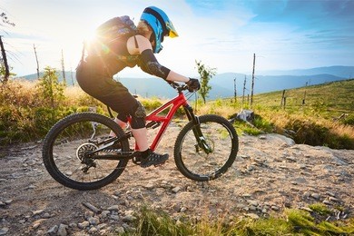 woman biking, riding mtb mountain bike during sunny summer day