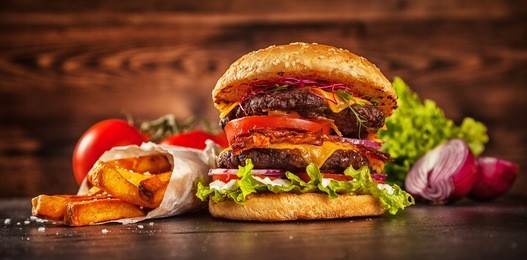 home made hamburger with lettuce, cheese, beef meat and french fries placed on old wooden table