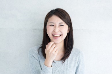 young asian woman laughing against concrete wall