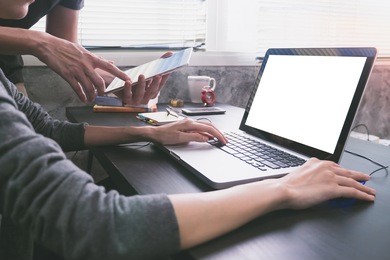 business partners working together at office desk, they are using a laptop with blank screen and tablet.