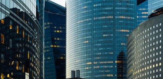 night architecture - skyscrapers with glass facade. modern buildings in paris business district. evening dynamic traffic on a street. concept of economics, financial.  copy space for text. toned